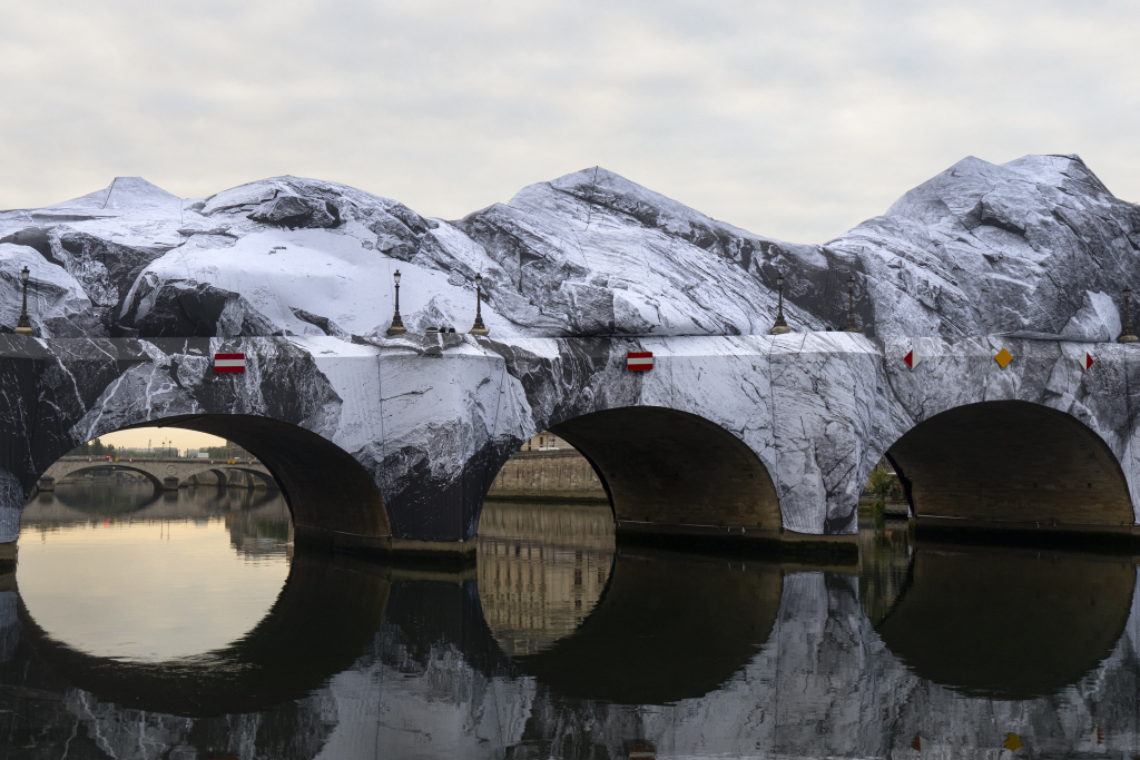 JR Pont Neuf Paris, wide view of La Caverne du Pont Neuf reflected in the still waters of the Seine, Paris, May 2026.